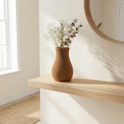 LUMA-vase i bronze med lyse blomster under et rundt spejl